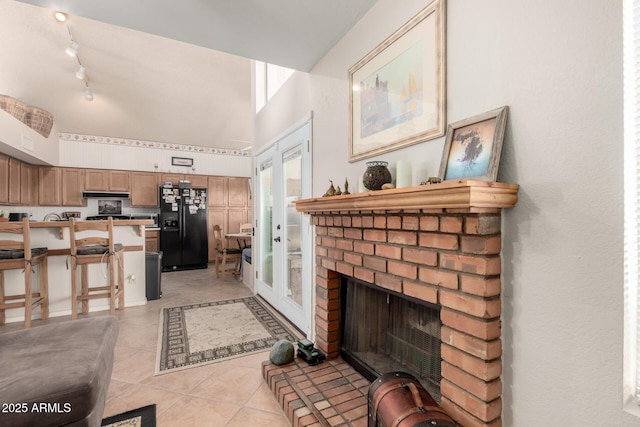 tiled living room featuring track lighting and a brick fireplace