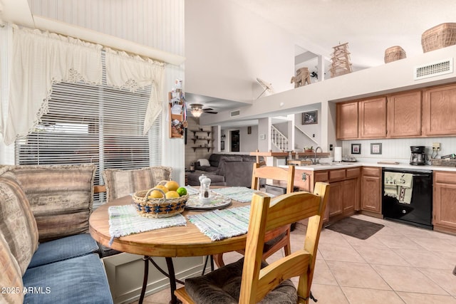 dining area featuring ceiling fan, a towering ceiling, sink, and light tile patterned floors