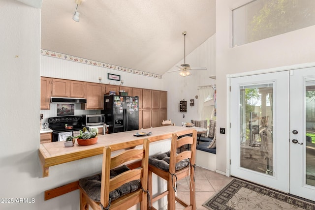 kitchen with lofted ceiling, french doors, black appliances, ceiling fan, and light tile patterned floors