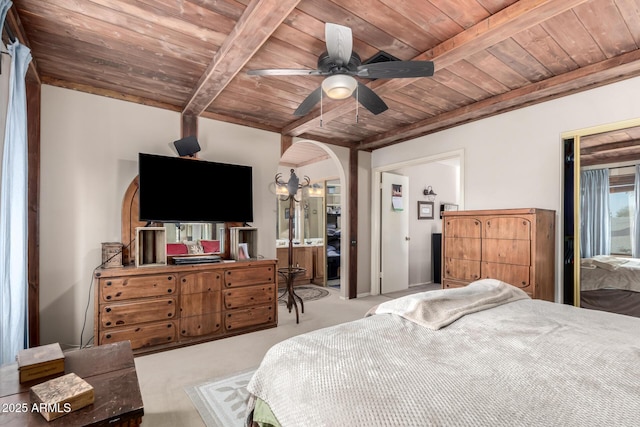 bedroom with beam ceiling, connected bathroom, ceiling fan, and wood ceiling