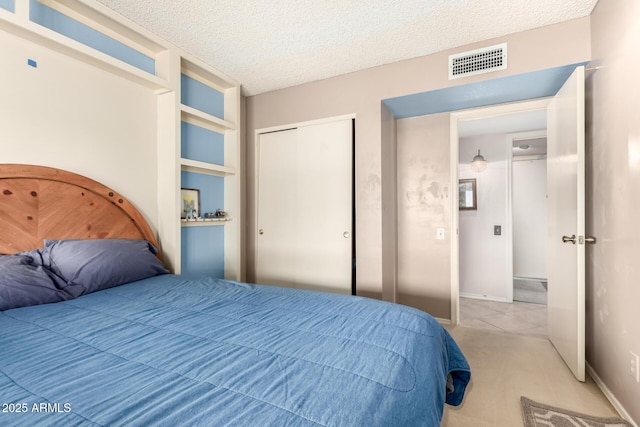 bedroom featuring light colored carpet, a textured ceiling, and a closet