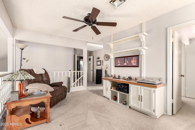 sitting room featuring ceiling fan, light colored carpet, and a textured ceiling