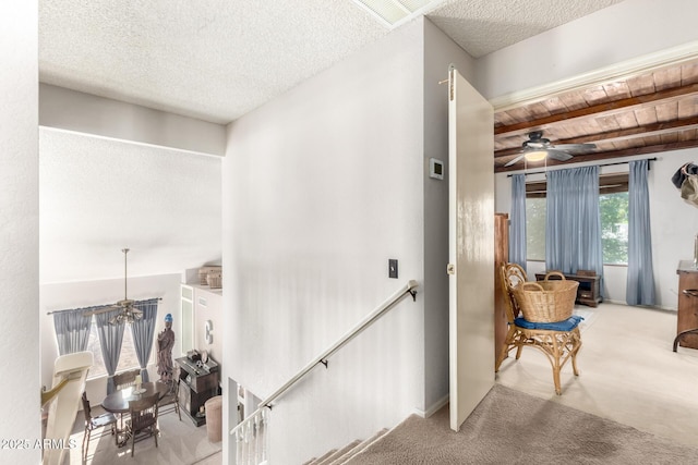 interior space featuring beamed ceiling, wood ceiling, light carpet, and a textured ceiling