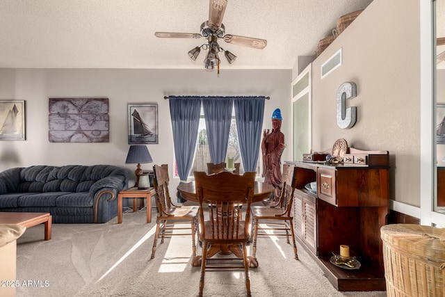 dining space with ceiling fan, carpet floors, and a textured ceiling