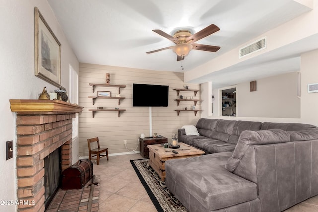 living room featuring a fireplace, light tile patterned flooring, ceiling fan, and wood walls