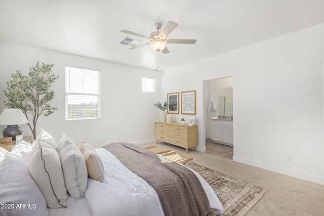 bedroom with baseboards, ensuite bath, a ceiling fan, and light carpet
