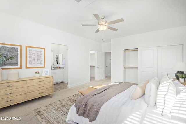 bedroom with a closet, ensuite bathroom, light colored carpet, and ceiling fan