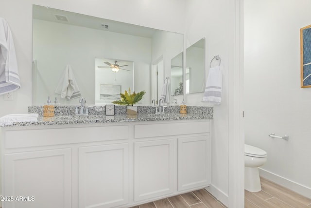 bathroom featuring wood finished floors, a ceiling fan, toilet, and double vanity