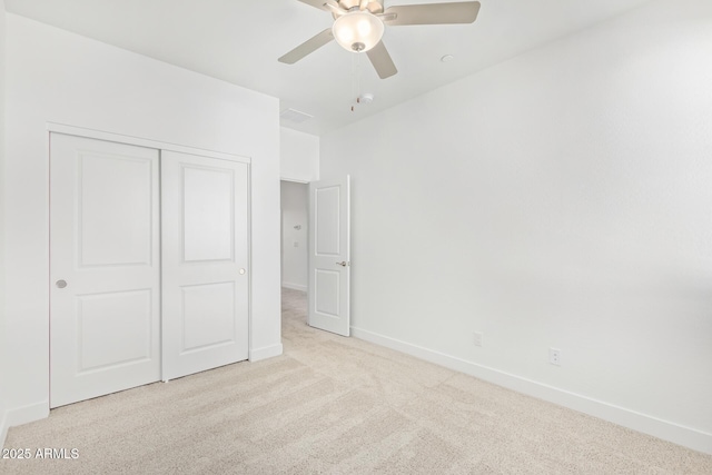 unfurnished bedroom with carpet floors, baseboards, a closet, and a ceiling fan