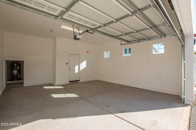 garage featuring a garage door opener, electric water heater, and baseboards