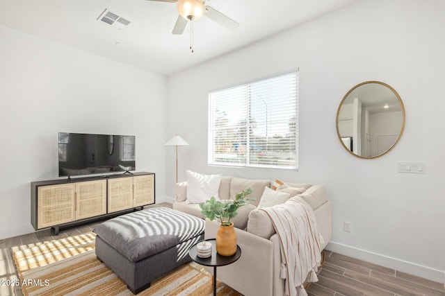 living area with baseboards, wood finished floors, and a ceiling fan