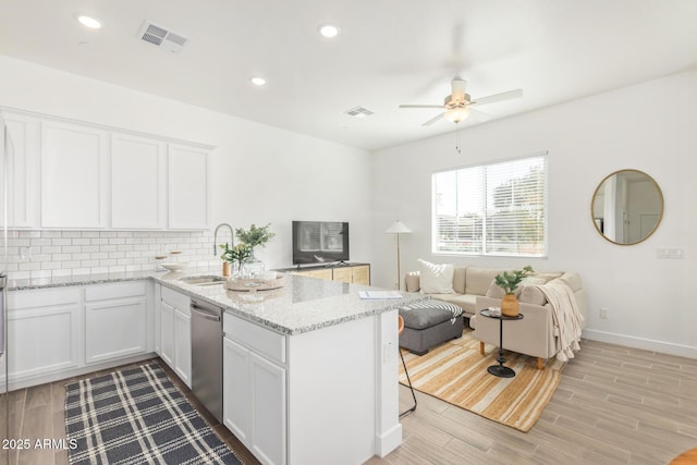 kitchen featuring a sink, stainless steel dishwasher, a peninsula, ceiling fan, and tasteful backsplash