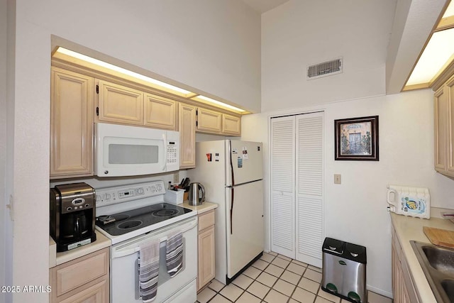 kitchen featuring a high ceiling, sink, light brown cabinets, and white appliances