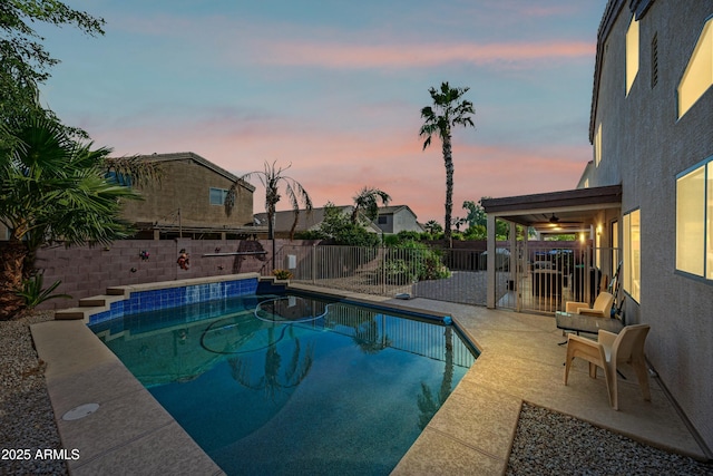 pool at dusk with ceiling fan and a patio