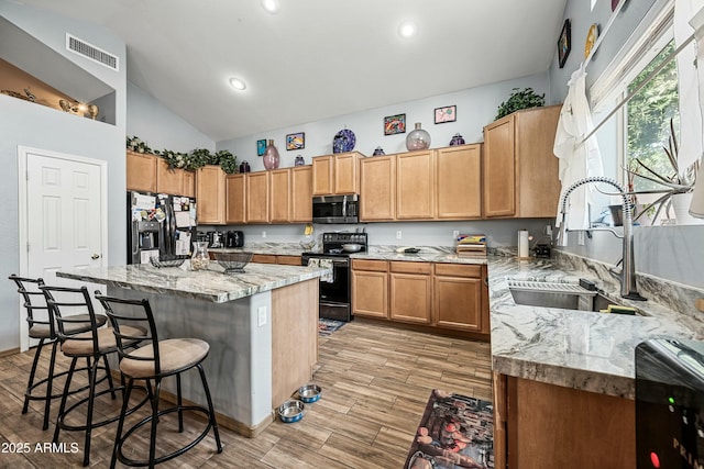 kitchen with stainless steel appliances, a center island, light stone counters, and sink