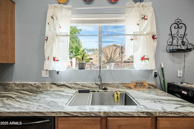 kitchen featuring light stone counters and dishwasher