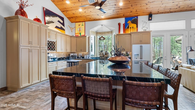 kitchen featuring dark countertops, ceiling fan, wood ceiling, high vaulted ceiling, and a breakfast bar area