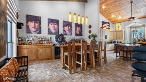 bar featuring high vaulted ceiling, a ceiling fan, a dry bar, and brick floor