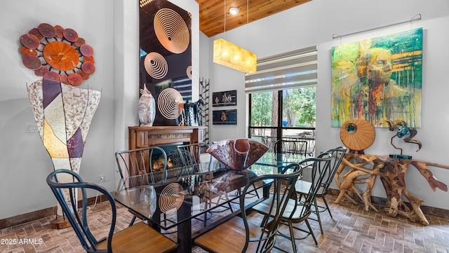 dining area featuring baseboards, recessed lighting, brick floor, wooden ceiling, and a lit fireplace