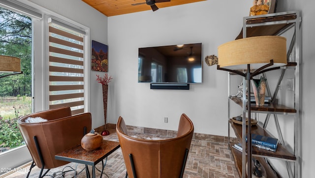 interior space with wood ceiling, brick floor, and ceiling fan