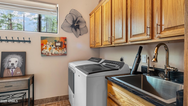 washroom with washing machine and clothes dryer, cabinet space, and a sink