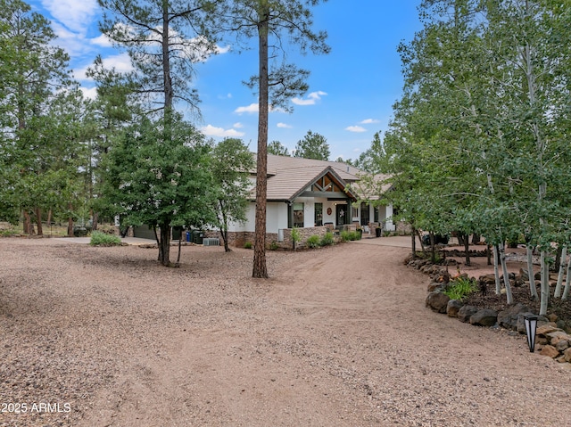 view of front facade with stone siding, a tile roof, curved driveway, and stucco siding