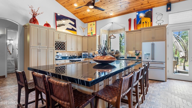 kitchen featuring high vaulted ceiling, white refrigerator with ice dispenser, wood ceiling, ceiling fan, and cream cabinets