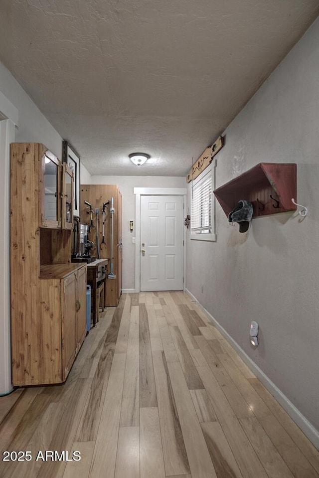 hallway featuring light hardwood / wood-style floors and a textured ceiling