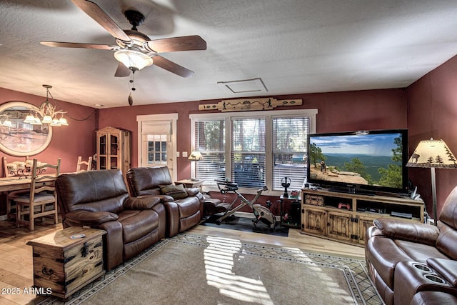 living room with ceiling fan with notable chandelier, light hardwood / wood-style floors, and a textured ceiling