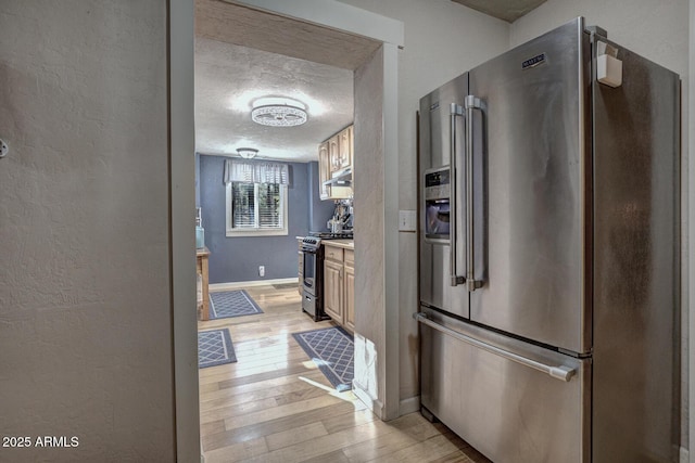 kitchen featuring light wood-type flooring, stainless steel appliances, and a textured ceiling