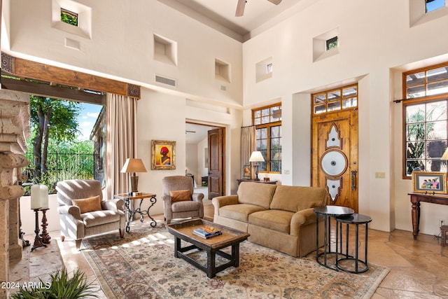 tiled living room with plenty of natural light, ceiling fan, and a high ceiling