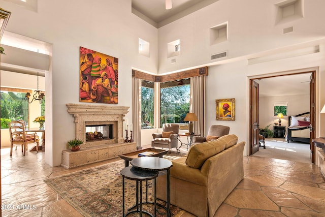 living room featuring tile floors, an inviting chandelier, a multi sided fireplace, and a high ceiling