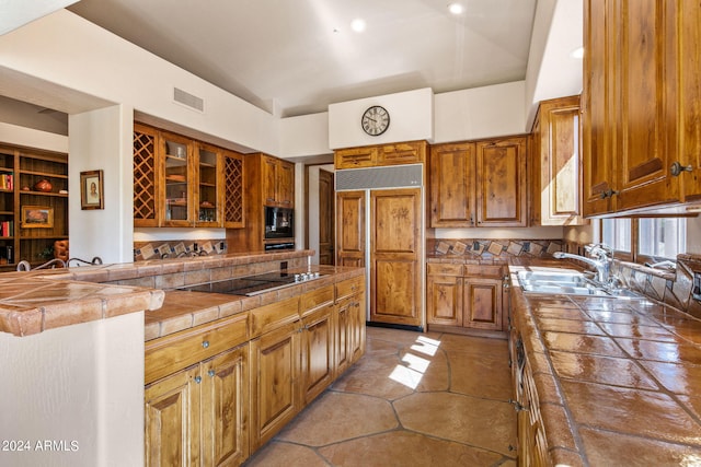 kitchen with tile counters, built in features, black appliances, sink, and light tile floors