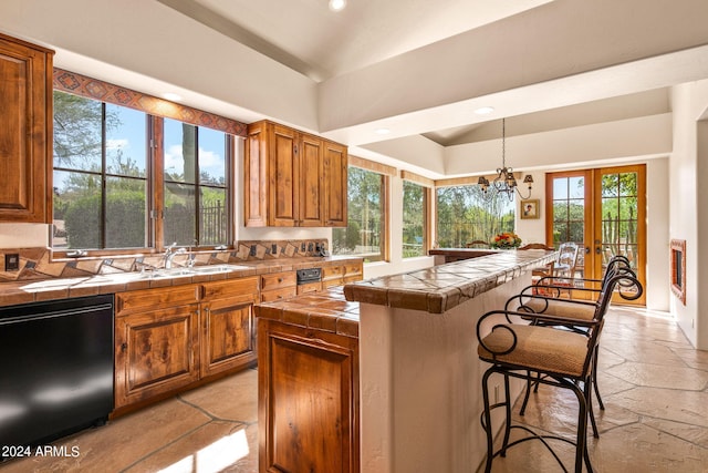 kitchen with decorative light fixtures, dishwasher, tile counters, and a wealth of natural light