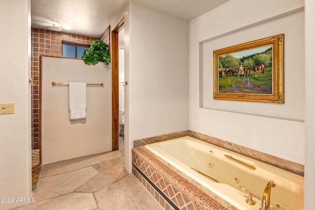 bathroom featuring tiled tub, toilet, tile floors, and a textured ceiling