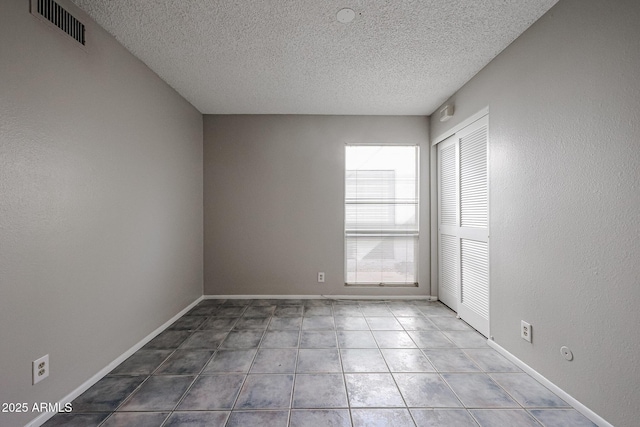 empty room with tile patterned flooring and a textured ceiling