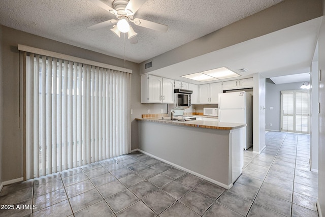 kitchen featuring white appliances, kitchen peninsula, ceiling fan, tile patterned flooring, and white cabinets