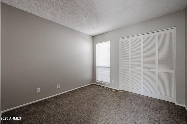 unfurnished bedroom featuring dark colored carpet, a textured ceiling, and a closet