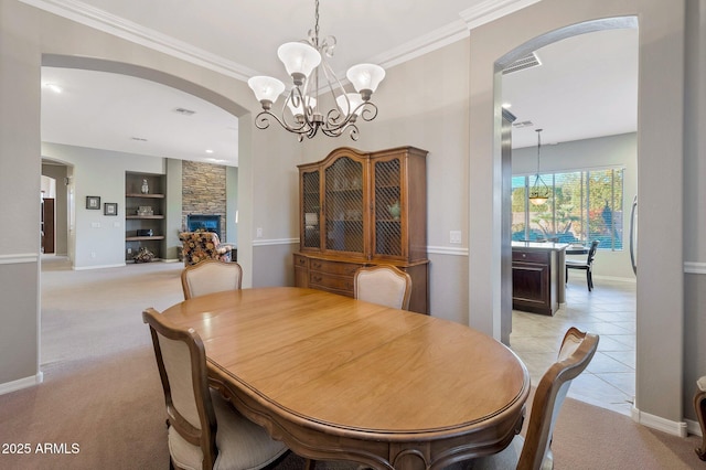 2472 E Prescott Pl, Chandler, AZ 85249 - dining room featuring arched walkways, built in features, a chandelier, a stone fireplace, and crown molding