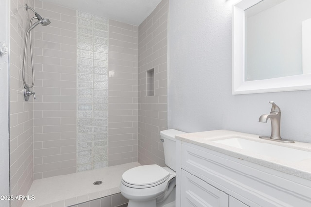 bathroom with vanity, toilet, and a tile shower