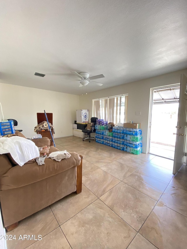 tiled living room with a textured ceiling and ceiling fan