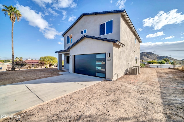 view of home's exterior with a mountain view, a garage, and central AC unit