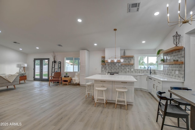 kitchen featuring lofted ceiling, pendant lighting, a center island, decorative backsplash, and white cabinetry