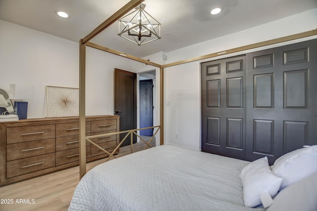 bedroom featuring a closet, light hardwood / wood-style flooring, and a notable chandelier