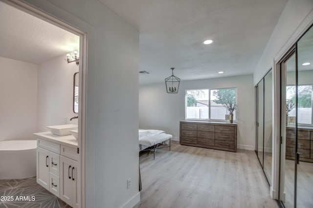 bathroom featuring hardwood / wood-style flooring, a tub, vanity, and a notable chandelier