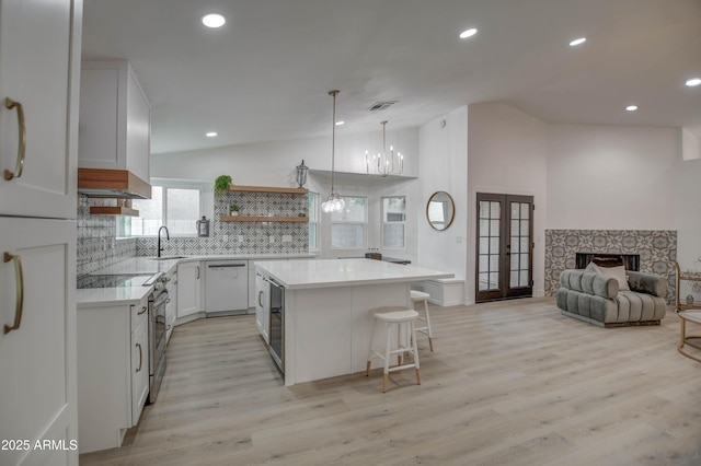 kitchen featuring decorative backsplash, dishwasher, french doors, white cabinets, and a center island