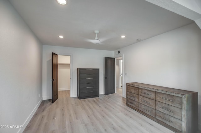 unfurnished bedroom with light wood-type flooring, a closet, a walk in closet, and ceiling fan