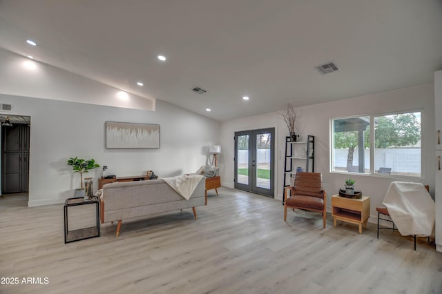 living area featuring light wood-type flooring, vaulted ceiling, and french doors