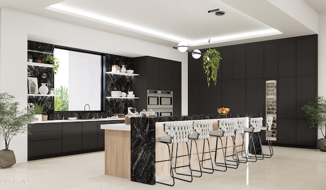 bar featuring stainless steel double oven, a tray ceiling, sink, and hanging light fixtures