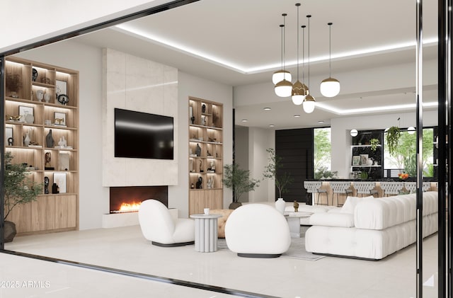 living room with a tiled fireplace, light tile patterned floors, built in features, and a raised ceiling